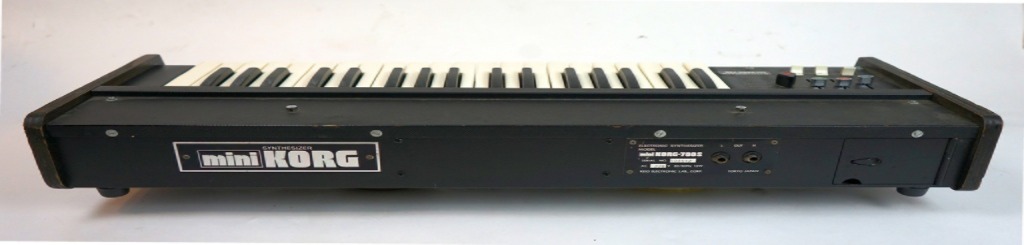 Rückseite des Korg Mini-Korg 700S Vintage-Analog-Synthesizers mit MiniKORG-Logo, Holzseitenteilen und Anschlussfeld.