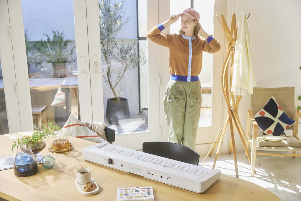 Casio CT-FS1WE mit vollständig weißer Tastatur auf einem Holztisch in einem sonnigen Wohnraum.